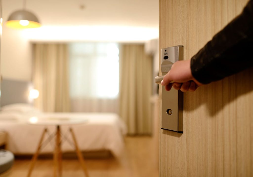 person-holding-on-door-lever-inside-room-271639 A soft-lit hotel room entrance, welcoming guests with luxury appeal and comfort.